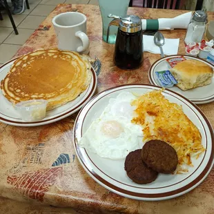 Two eggs over easy with crisp hash browns, Patty sausage, biscuit and one yummy pancake.