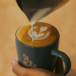 a person pouring milk into a cup of coffee