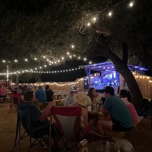 a large group of people sitting at tables under a tree