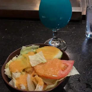 a bowl of salad and a drink