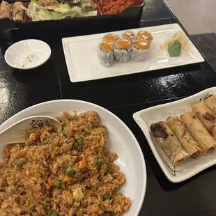Spicy vegetable fried rice, salmon meal across, spicy ca roll in the center and spring roll at right.