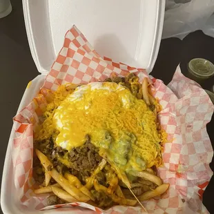 a container of fries with cheese on top