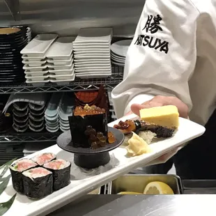 a chef holding a plate of sushi
