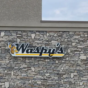 a brick wall with a sign that says waspy's