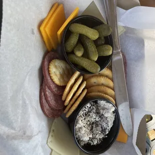 a plate of cheese, crackers, and pickles