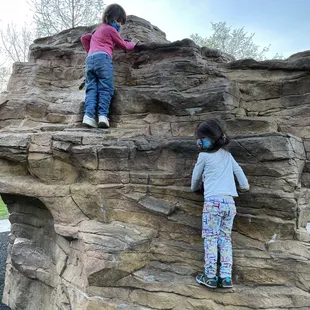 Masked children climbing a rock structure
