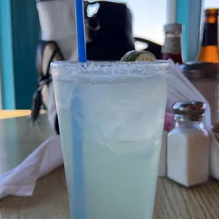 a glass of margarita with a blue straw