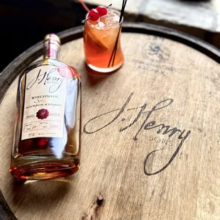 a bottle of alcohol and a glass with a cherry garnish