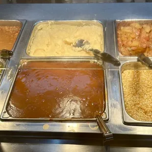 Hot vegetables on the buffet. Corn, apples, mashed potatoes, gravy, green beans.