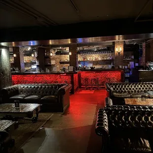 a dimly lit bar with leather couches