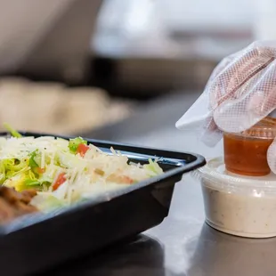 a person putting sauce in a container