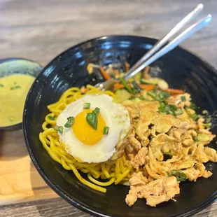 a bowl of noodles with a fried egg on top