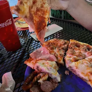 a hand holding a slice of pizza