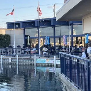 people sitting at tables on a pier