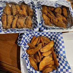 two trays of chicken wings and fries