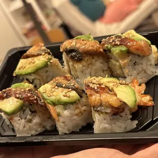 a person holding a tray of sushi