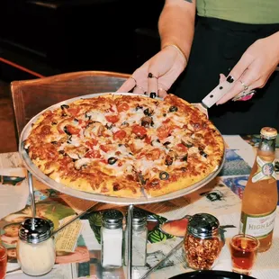 a person cutting a pizza