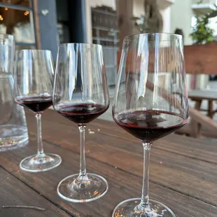 a row of wine glasses on a wooden table