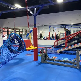 Play area with zip line, roller slide, inner tube swing, tunnel net, bridge.