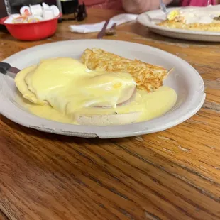 a plate of eggs benedict with a side of hash browns