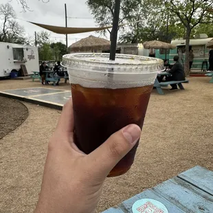 a hand holding a cup of iced coffee