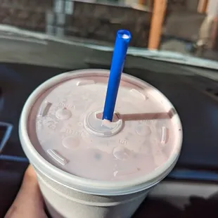 a hand holding a plastic cup with a blue straw