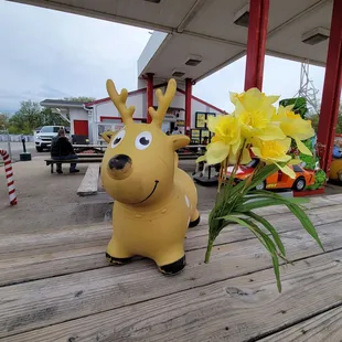 a yellow deer with flowers in a vase