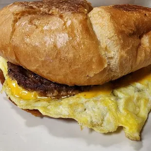 Breakfast sandwich with sausage, egg, and cheese on croissant.