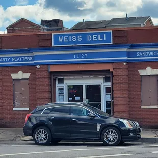 a car parked in front of a deli