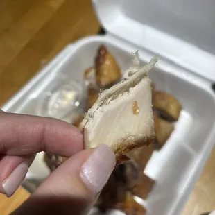 a person holding a piece of food in a styrofoam container