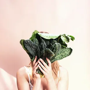 a woman covering her face with a bunch of broccoli