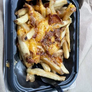 a tray of fries with cheese on top