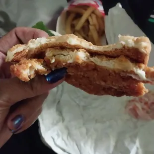 a hand holding a half eaten sandwich