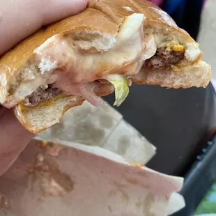 a hand holding a half eaten sandwich