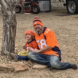 a man and a child sitting under a tree