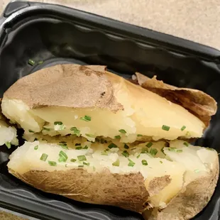 a close up of a baked potato in a styrofoam container