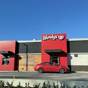 a red car parked in front of a wendy's