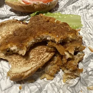 a half eaten sandwich on a piece of tin foil