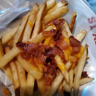 a plate of french fries with bacon and cheese