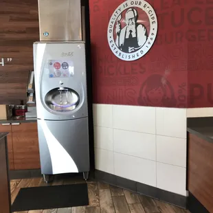 a kitchen with a refrigerator and a logo on the wall