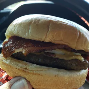 a hand holding a sausage and egg sandwich