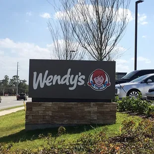 a sign for wendy&apos;s with cars in the background