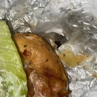 a piece of chicken wrapped in foil with a pickle