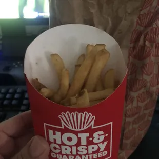 a hand holding a box of fries