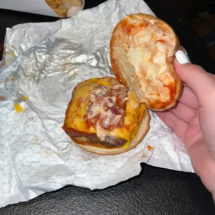 a hand holding a half eaten cheeseburger