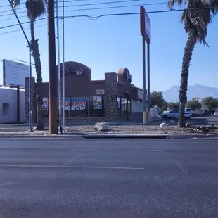 an empty street with palm trees in the foreground