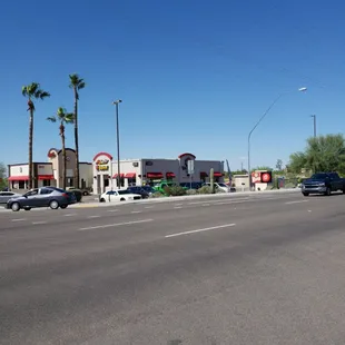 a view of a street with cars and palm trees