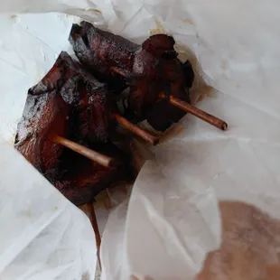 a hand holding a skewer of meat