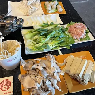 (From top left) homemade noodles, pork dumplings, melon, Chinese book choy, chicken thighs, enoki mushrooms, oyster mushrooms and tofu skin