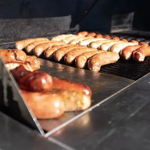 hot dogs cooking on a grill